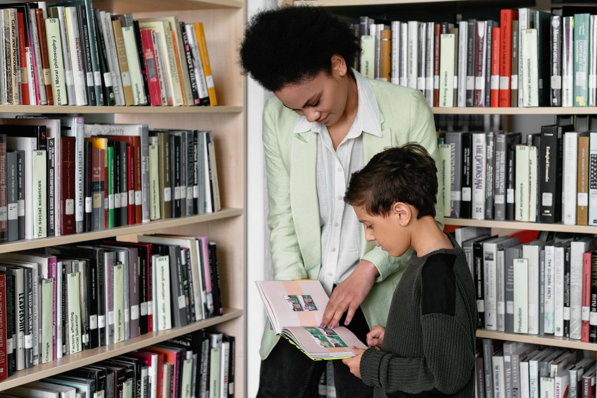 Teacher helping child read in a library